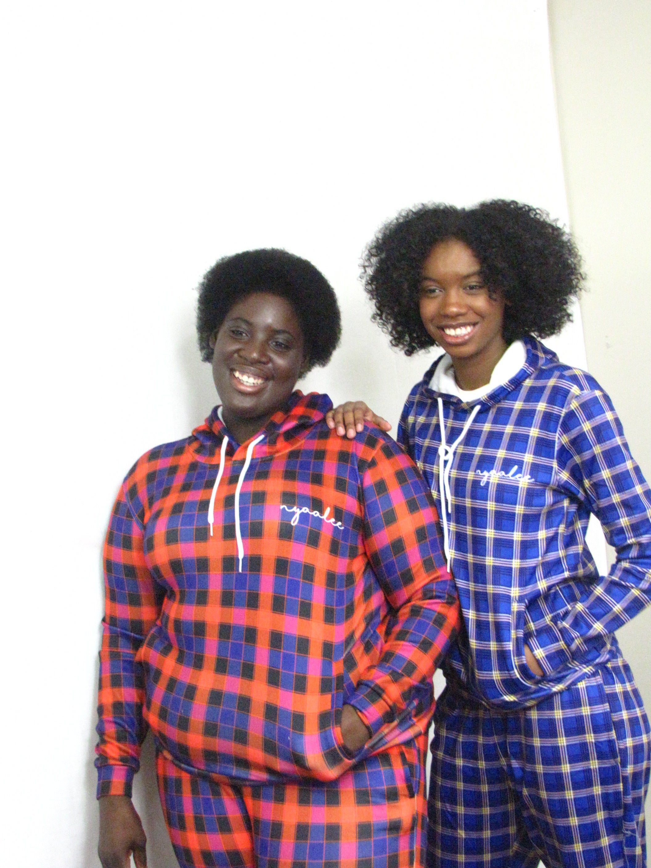 Two women smiling together while the women in stripe blue tracksuit has her hand on the shoulder of the women in the stripe purple